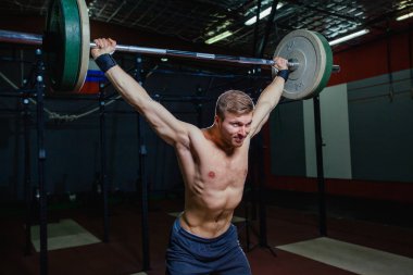 Yakışıklı bir atlet portresi. Atlet halter başının üzerine yükseltir. çekim koyu tonda. Çapraz tarzı uygun, deadlift