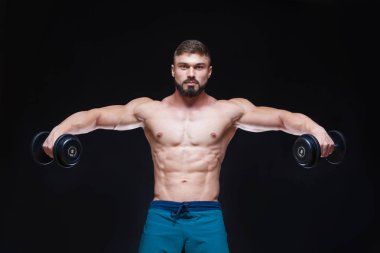 Siyah arka plan üzerinde halter alıştırmalar yapan kaslı vücut geliştirmeci adam