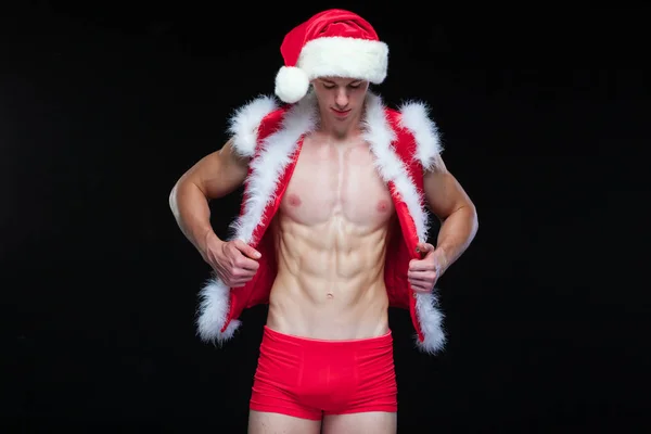 Babbo Natale sexy. Il giovane uomo muscoloso che indossa il cappello di Babbo Natale dimostra i suoi muscoli. Isolato su sfondo nero. — Foto Stock