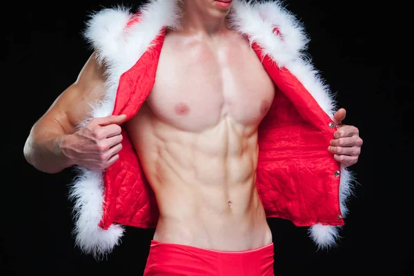 Seksowny Święty Mikołaj. Młody muskularny mężczyzna w kapeluszu Świętego Mikołaja demonstruje swoje mięśnie. Izolacja na czarnym tle. — Zdjęcie stockowe