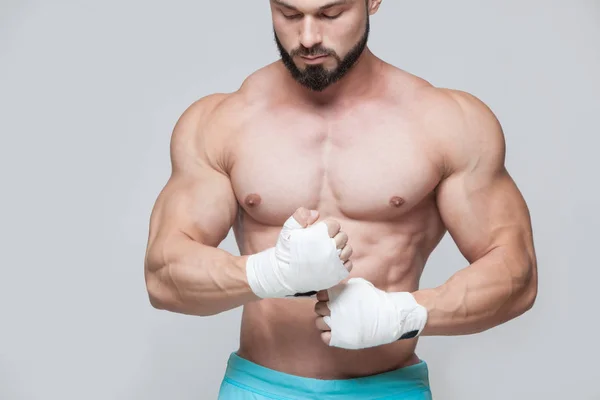 Muscular Fighter kickbox con vendajes blancos contra el fondo gris —  Fotos de Stock