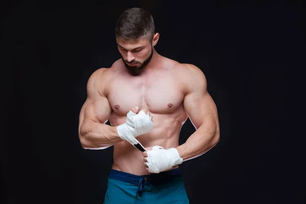 Muscular Fighter kickbox con vendajes blancos contra el fondo negro . — Foto de Stock
