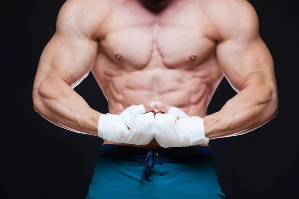 Muskulöser Kämpfer-Kickbox mit weißen Binden vor schwarzem Hintergrund. — Stockfoto