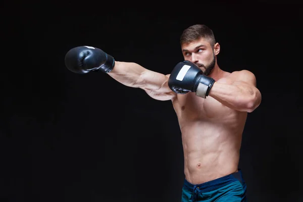 Kräftiger muskulöser Boxer in schwarzen Boxhandschuhen. isoliert auf schwarzem Hintergrund. — Stockfoto