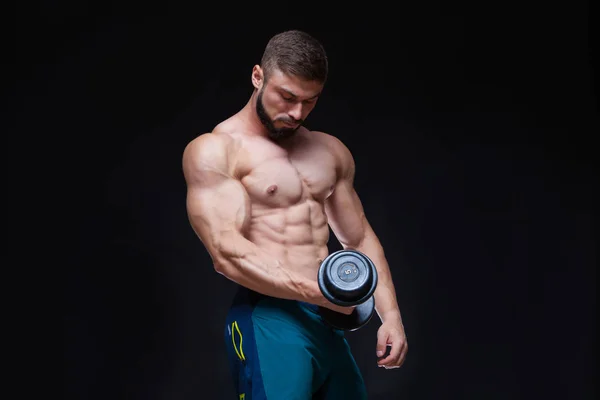 Muscular culturista chico haciendo ejercicios con mancuerna sobre fondo negro —  Fotos de Stock