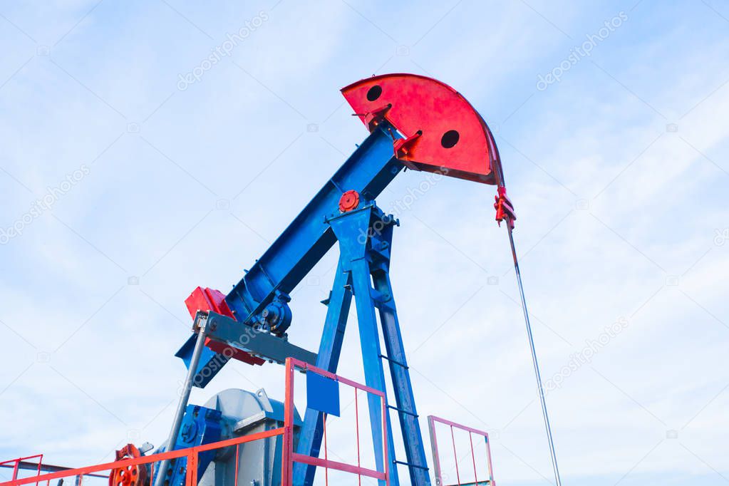 The oil pump, industrial equipment. Oil field site, oil pumps are running. Rocking machines for oil production in a private sector.