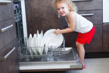 sevimli sarışın bebek kız mutfakta tabak bulaşık yıkama makinesi dışına alarak yardım