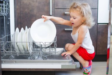 sevimli sarışın bebek kız mutfakta tabak bulaşık yıkama makinesi dışına alarak yardım