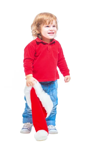 Рождество. Маленький мальчик в шляпе Санты, в красной куртке и синих джинсах. Изолированный на белом фоне . — стоковое фото
