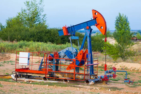 La pompa dell'olio, attrezzature industriali. Sito del giacimento petrolifero, le pompe dell'olio sono in funzione. Macchine a dondolo per la produzione di petrolio in un settore privato . — Foto Stock