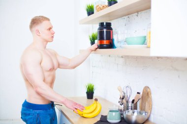 Çıplak bir gövde mutfak sağlıklı beslenme kavramı ile bir spor beslenme protein ve muz, kaslı adam. Atletik yaşam tarzının.