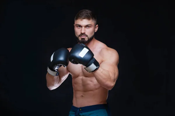 Boxeador musculoso fuerte con guantes de boxeo negros. Aislado sobre fondo negro . — Foto de Stock
