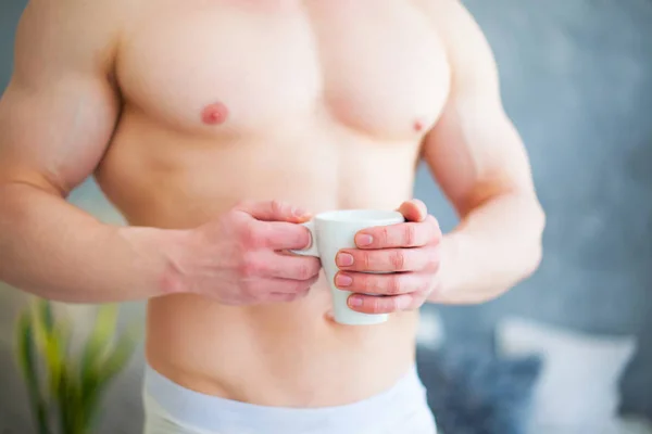 Sexy bonito jovem de pé sem camisa em seu quarto, segurando uma xícara de café — Fotografia de Stock