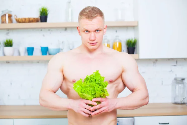 Homem musculoso com um tronco nu na cozinha com uma salada, conceito de alimentação saudável. Modo de vida atlético . — Fotografia de Stock