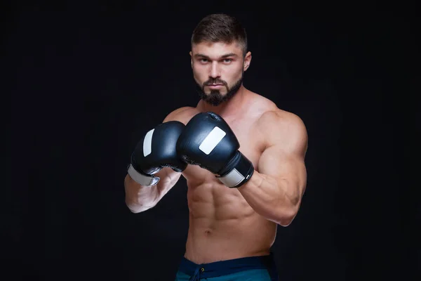 Kräftiger muskulöser Boxer in schwarzen Boxhandschuhen. isoliert auf schwarzem Hintergrund. — Stockfoto