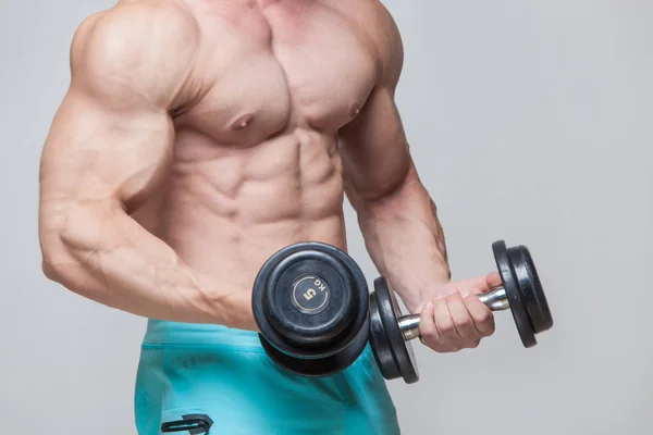 Gespierde bodybuilder man doen oefeningen met dumbbell over grijze achtergrond — Stockfoto