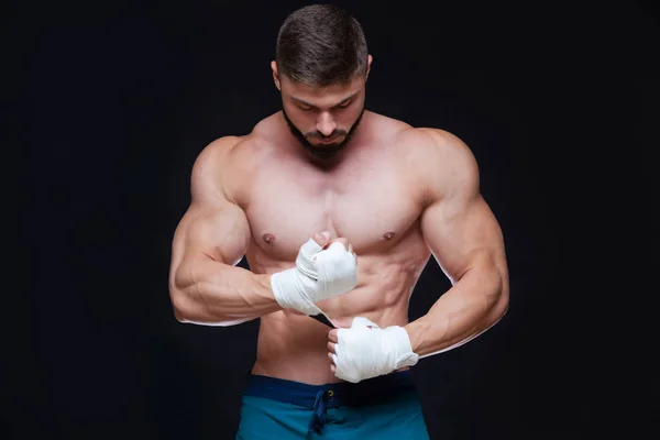 Kickbox combattente muscolare con fasciature bianche contro lo sfondo nero . — Foto Stock