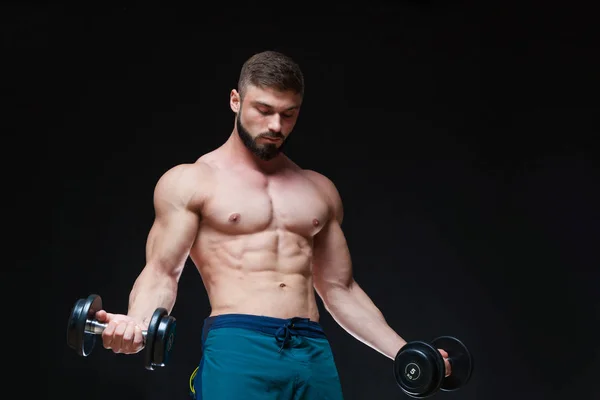 Gespierde bodybuilder man doen oefeningen met dumbbell op zwarte achtergrond — Stockfoto