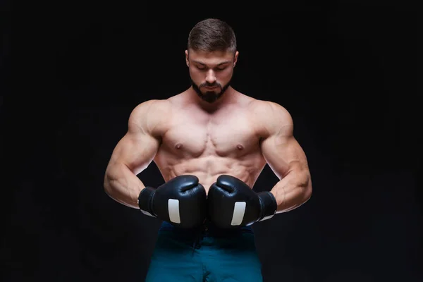 Kräftiger muskulöser Boxer in schwarzen Boxhandschuhen. isoliert auf schwarzem Hintergrund. — Stockfoto