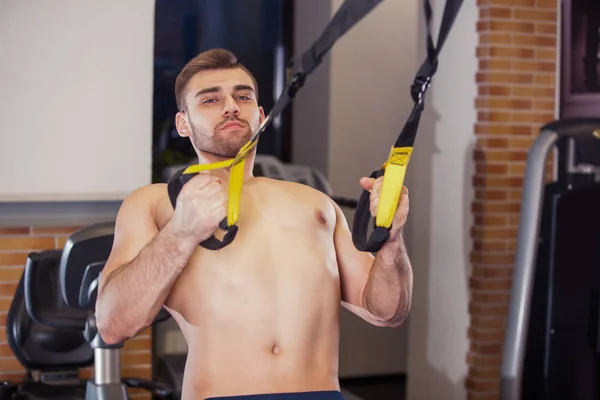Hombre atractivo hace Crossfit Empuje Ups con correas de fitness Trx en el estudio de gimnasios — Foto de Stock