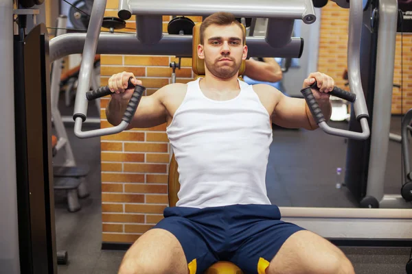 Hombre haciendo ejercicio en el gimnasio. Atleta de fitness haciendo ejercicios de pecho en la máquina de press de banca vertical —  Fotos de Stock