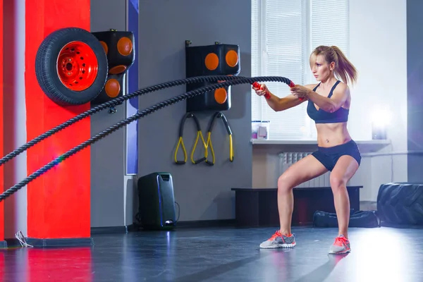 Mulher treinando com corda de batalha em cross fit ginásio — Fotografia de Stock