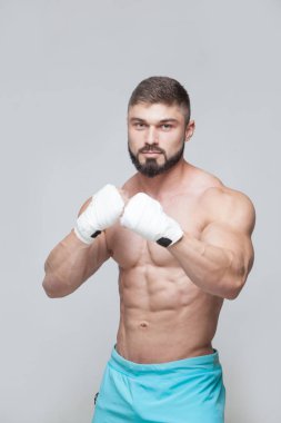 Gri arka planı beyaz bandaj ile kaslı savaşçı kickbox