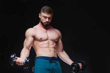 Siyah arka plan üzerinde halter alıştırmalar yapan kaslı vücut geliştirmeci adam