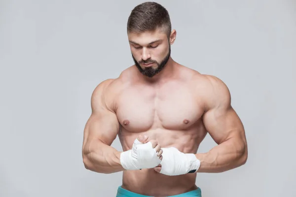 Muskulös Fighter kickbox med vitt bandage mot grå bakgrund — Stockfoto