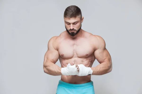 Muscular Fighter kickbox con vendajes blancos contra el fondo gris — Foto de Stock