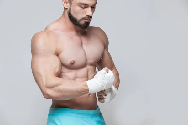 Muscular Fighter kickbox con vendajes blancos contra el fondo gris —  Fotos de Stock