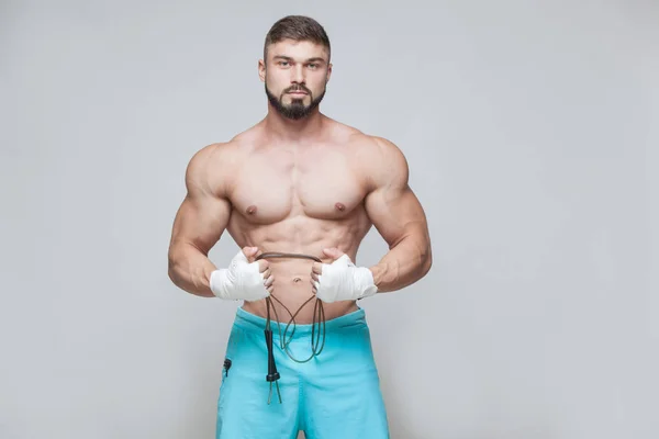 Sport, attività. Kickbox Combattente Muscolare con corda da salto. Muscolari uomini sfondo grigio . — Foto Stock