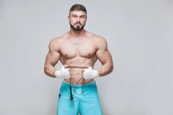 Deporte, actividad. Muscular Fighter kickbox con saltar la cuerda. Hombres musculares fondo gris . — Foto de Stock