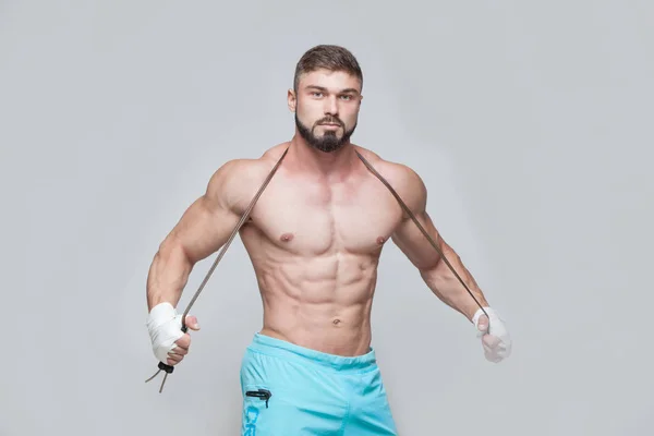 Deporte, actividad. Muscular Fighter kickbox con saltar la cuerda. Hombres musculares fondo gris . — Foto de Stock