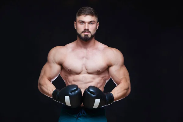 Kräftiger muskulöser Boxer in schwarzen Boxhandschuhen. isoliert auf schwarzem Hintergrund. — Stockfoto