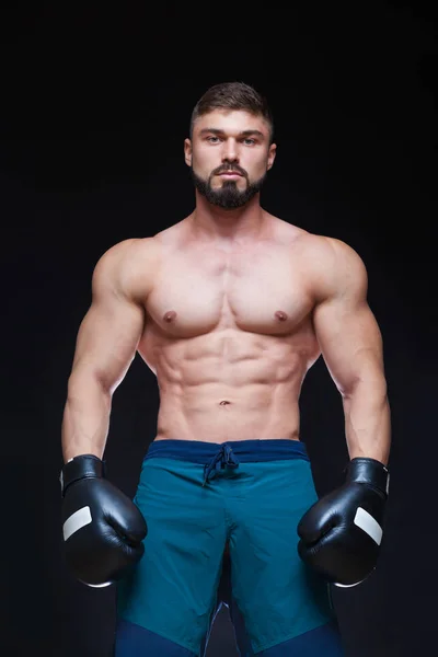 Silný svalnatý boxer v černých Boxerské rukavice. Izolované na černém pozadí. — Stock fotografie