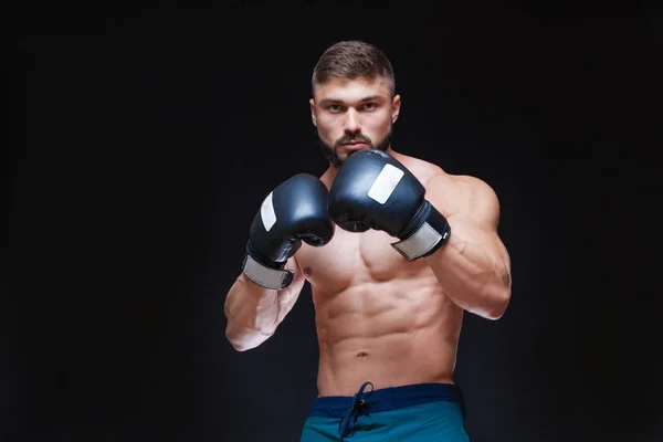 Kräftiger muskulöser Boxer in schwarzen Boxhandschuhen. isoliert auf schwarzem Hintergrund. — Stockfoto