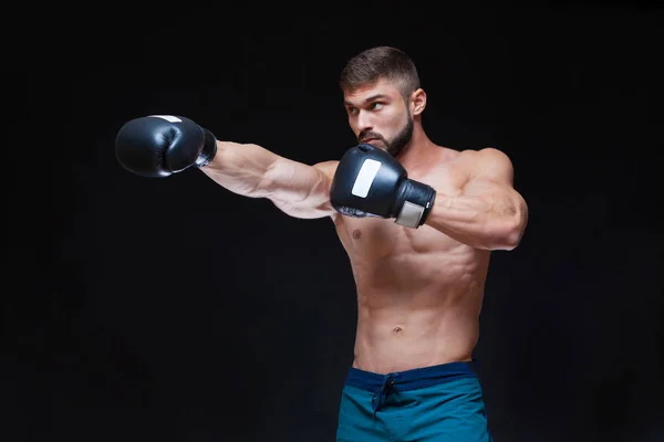 Boxeador musculoso fuerte con guantes de boxeo negros. Aislado sobre fondo negro . — Foto de Stock