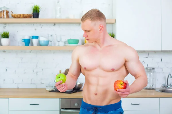 Svalnatý muž nahý trup v kuchyni s ovocem, koncept zdravého stravování. Sportovní způsob života. — Stock fotografie