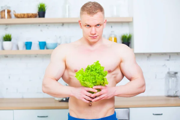 Muskulös man med en naken torso i köket med en sallad, begreppet hälsosam kost. Atletisk livsföring. — Stockfoto