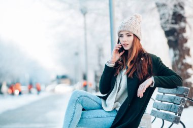 Akıllı telefon ve kış manzarası ile gülümseyen genç kadın .