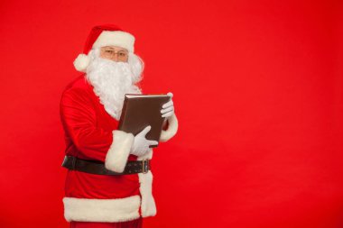 Noel Baba kırmızı bir arka plan üzerinde eski kitap okur. Noel