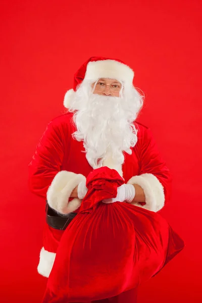Porträtt av jultomten med stor röd säck tittar på kameran — Stockfoto