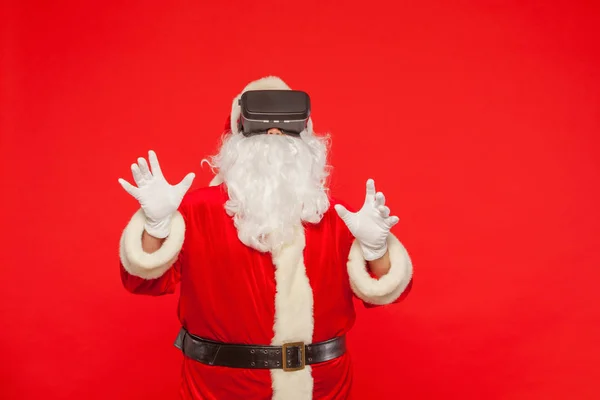 Père Noël portant des lunettes de réalité virtuelle, sur un fond rouge — Photo