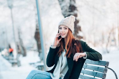 Akıllı telefon ve kış manzarası ile gülümseyen genç kadın