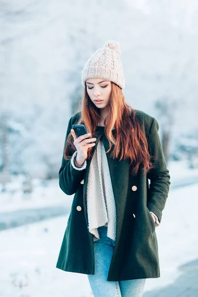 Fiatal nő, mosolygós, szúró telefon és a téli táj . — Stock Fotó