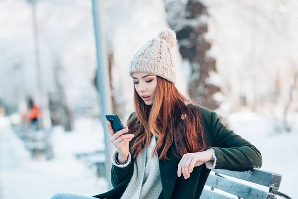 Fiatal nő, mosolygós, szúró telefon és a téli táj . — Stock Fotó