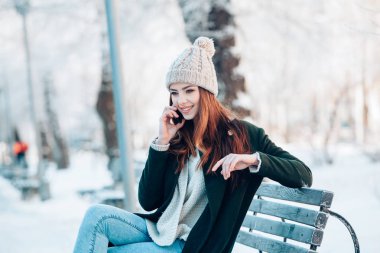 Akıllı telefon ve kış manzarası ile gülümseyen genç kadın .