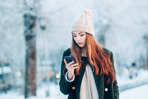 Junge Frau lächelt mit Smartphone und Winterlandschaft . — Stockfoto