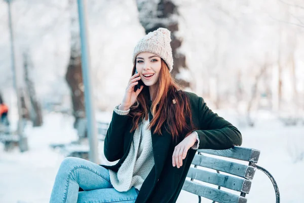 Junge Frau lächelt mit Smartphone und Winterlandschaft . — Stockfoto